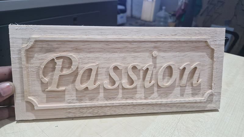 Script lettering engraved into a moulded name plate, fine detail work in thin board