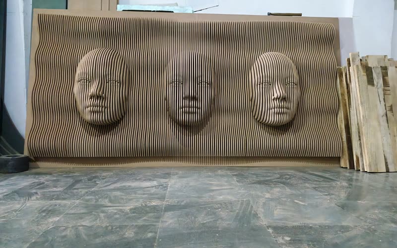 CNC cut parametric wall panel with carved faces rising out of a stacked-rib field, in MDF